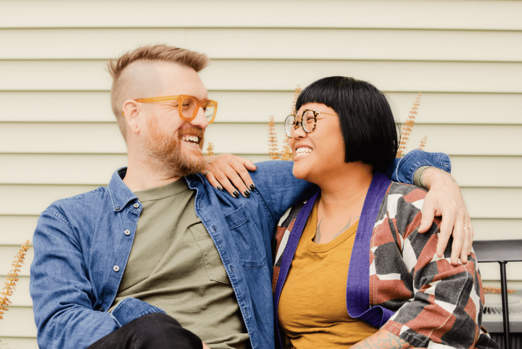 Two people sitting in a bench smiling at each other